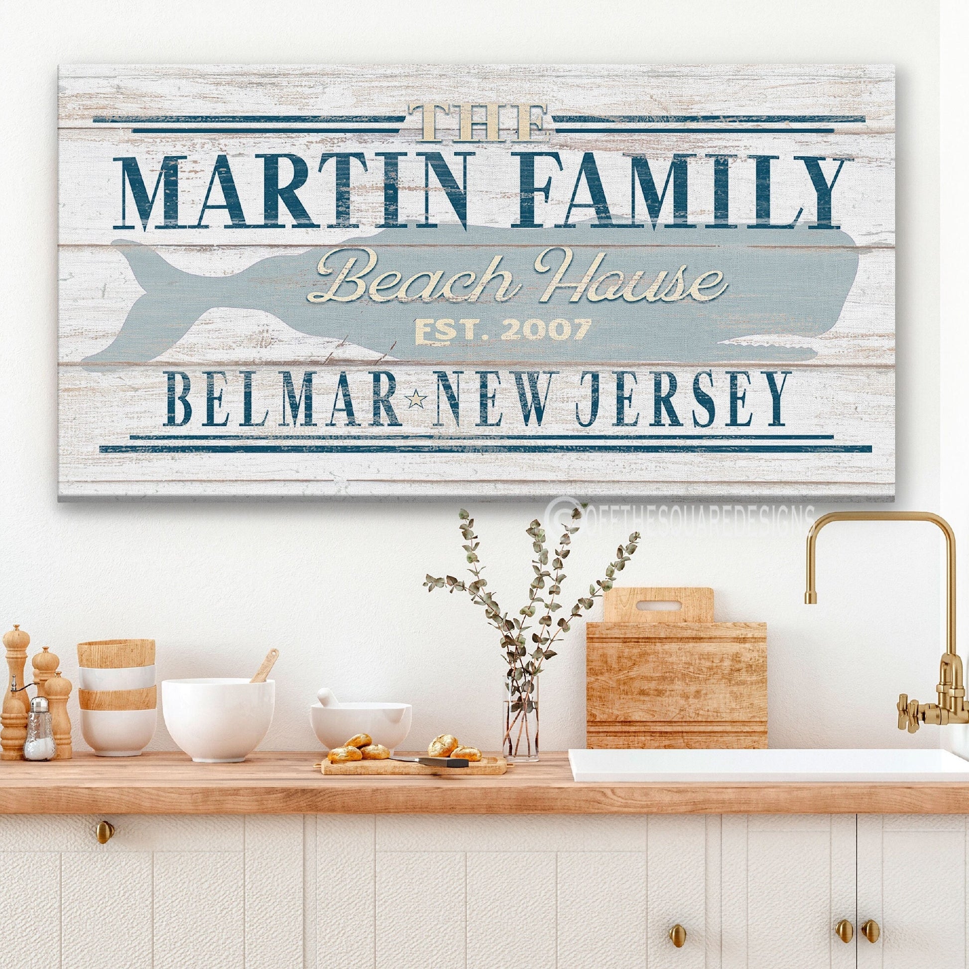 Personalized beach house whale sign with family name displayed above kitchen sink in coastal home