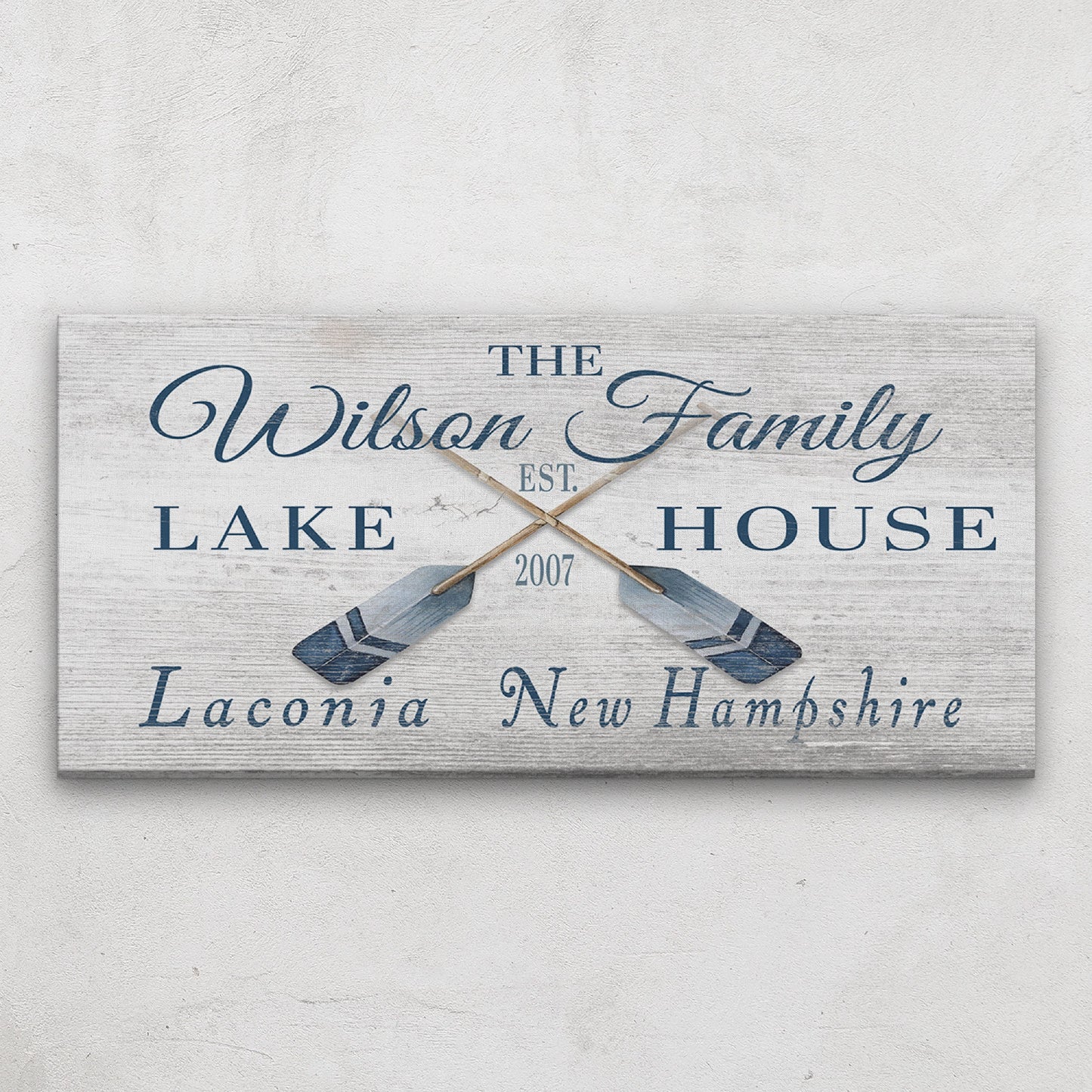Personalized latitude longitude sign above bed in coastal bedroom with beach-inspired bedding