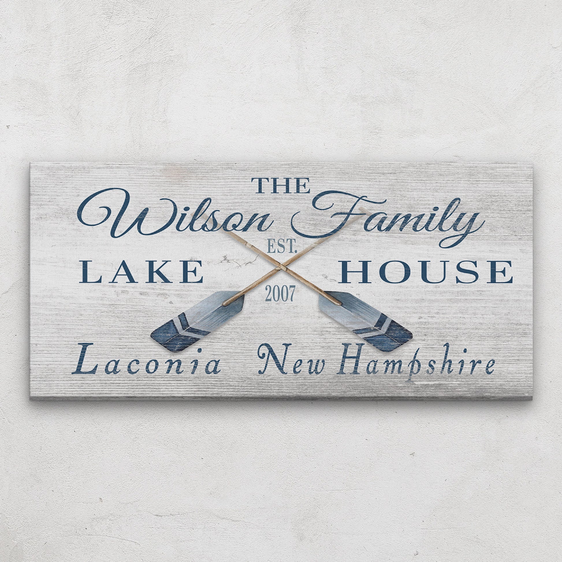 Personalized latitude longitude sign above bed in coastal bedroom with beach-inspired bedding