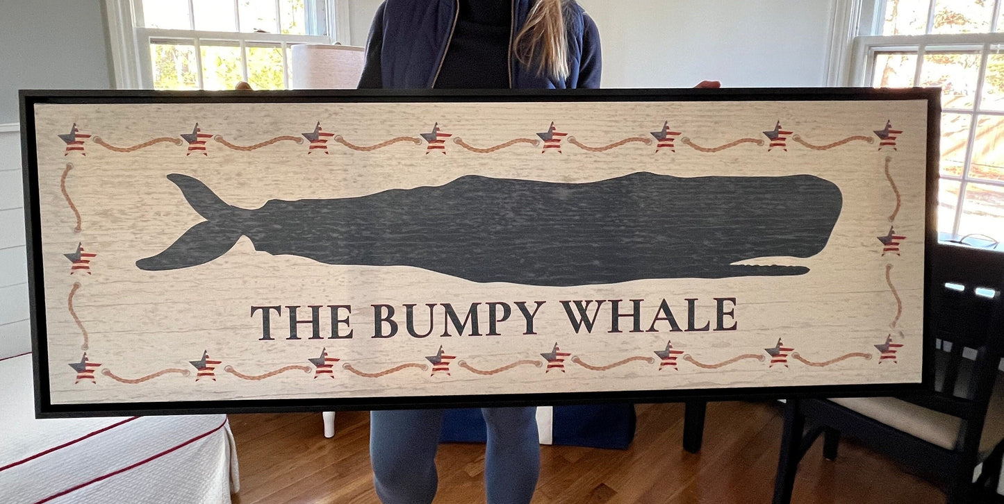 Framed whale sign as statement piece above fireplace anchoring nautical coastal living room decor